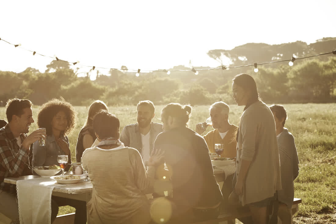 Friends sharing dinner at golden hour under string lights