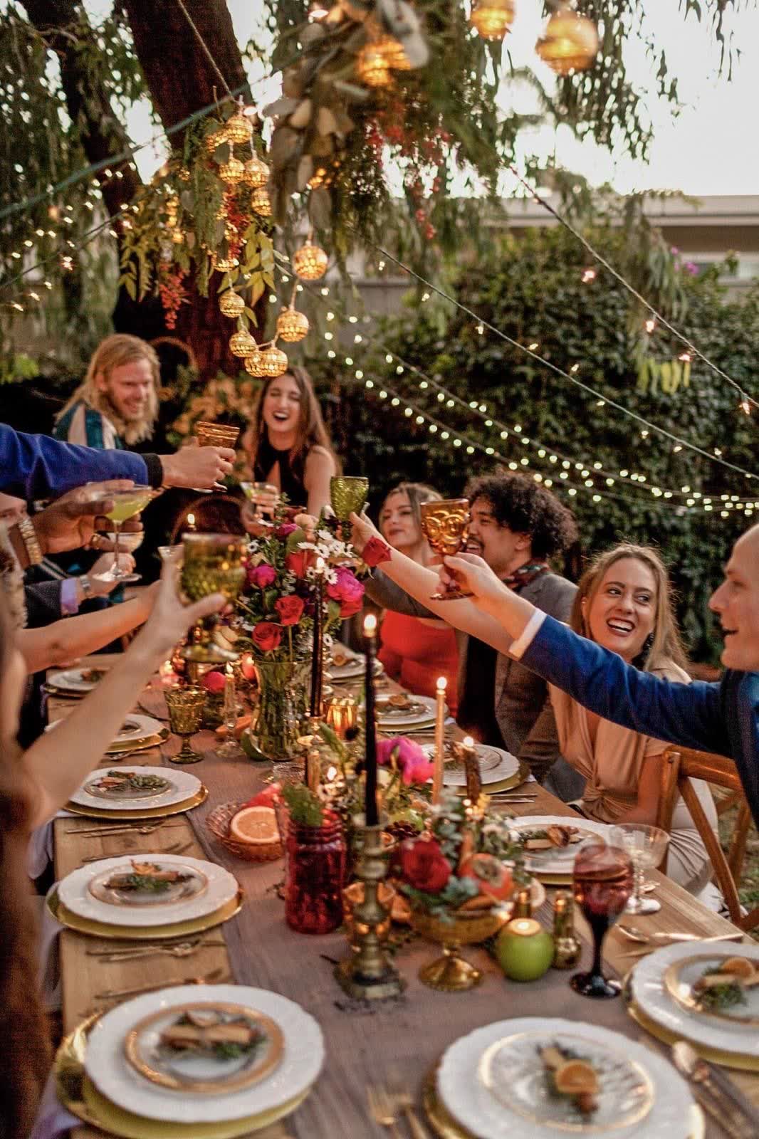 A garden dinner party raising a toast under hanging lanterns
